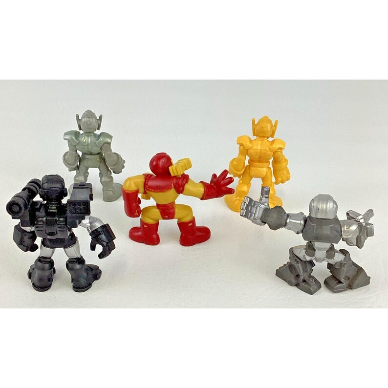 May include: A collection of five colorful toy robots. The robots are in various poses and colors, including red, yellow, gray, and black. The toys are made of plastic and have a cartoonish design.