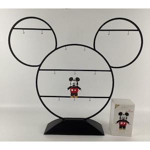 May include: Black metal Mickey Mouse-shaped display stand with hooks for ornaments. A Mickey Mouse ornament is displayed in the center. A Hallmark box with a Mickey Mouse image is on the right.