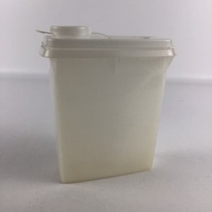 Puede incluir: Un recipiente de plástico blanco con una tapa con bisagras. El recipiente tiene un pico en la parte superior.