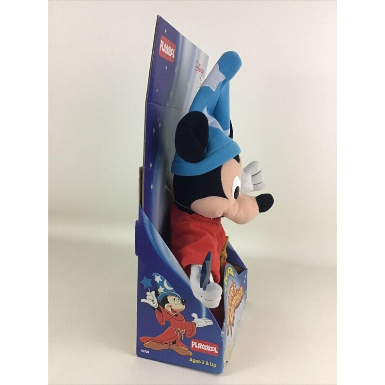May include: A blue and red plush Mickey Mouse toy dressed as a wizard. The toy is holding a wand and is packaged in a blue and white box with the Playskool logo and the words "Ages 2 & Up".