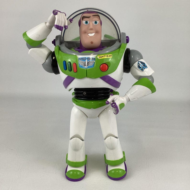 May include: A Buzz Lightyear action figure, featuring a green, white, and purple spacesuit. The figure has a clear helmet, a smiling face, and the words "SPACE RANGER" and "LIGHTYEAR" printed on the chest. The figure is posed with one arm raised.