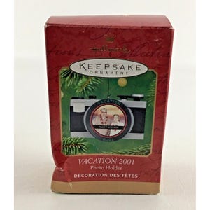 May include: Red and white box with a Hallmark Keepsake Ornament inside. The ornament is a black and silver camera with a round photo frame that says "Vacation 2001" and "Place Photo Here".