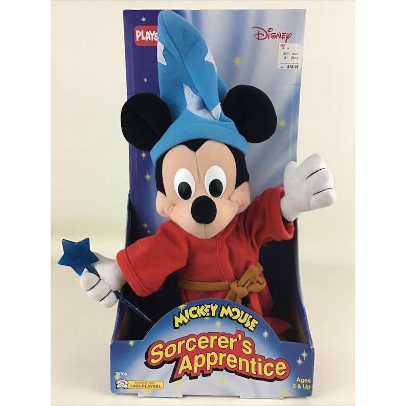 May include: A plush Mickey Mouse toy dressed as Sorcerer's Apprentice from the Disney movie Fantasia. He is wearing a blue hat, red robe, and holding a blue star-shaped wand. The packaging features the Disney logo and the words "Mickey Mouse Sorcerer's Apprentice".