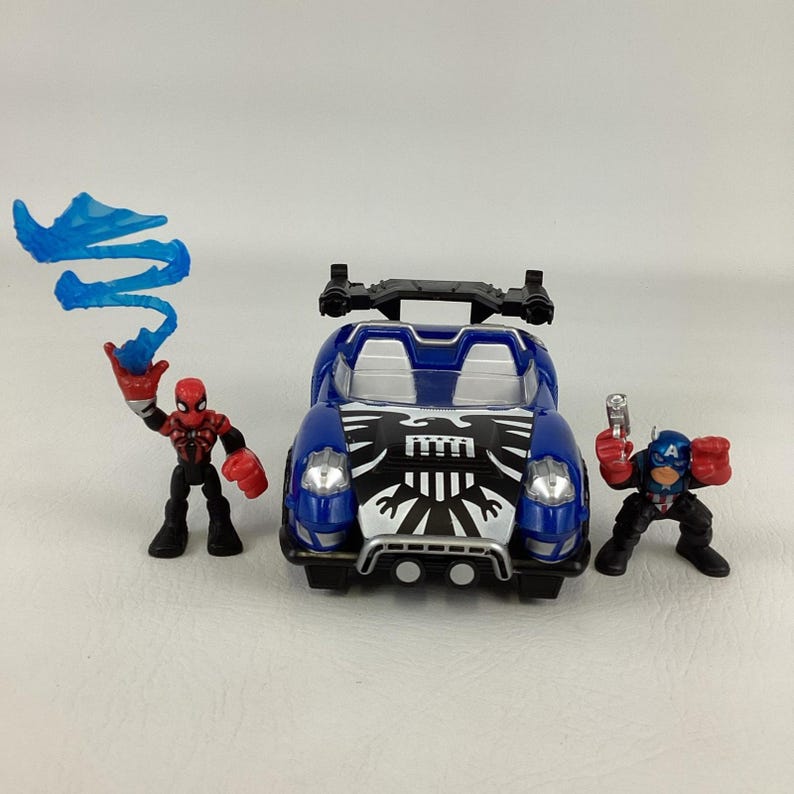 May include: A blue toy car with a black and white design on the hood, flanked by two action figures. One figure is Spider-Man, the other is Captain America. Spider-Man is holding a blue web-like accessory.