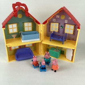 May include: A yellow, two-storey doll's house with a red roof, open to show interior rooms. The rooms are furnished with miniature furniture and include several Peppa Pig figurines. The doll's house has a red handle for carrying.