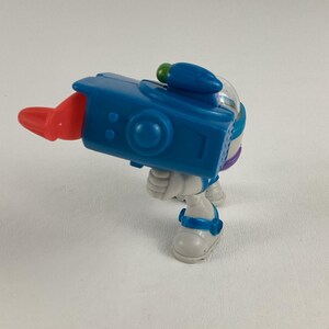 Op de afbeelding: Een blauw en wit speelgoed ruimteranger figuur met een rode projectiellanceerder. Het speelgoed heeft een blauwe helm, witte laarzen en een blauwe blaster. Het speelgoed is een leuk verzamelobject.