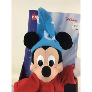 May include: A plush Mickey Mouse wearing a blue wizard hat and red robe. The toy is in a box with the words "PLAYSKOOL" and "DISNEY" on it. The price tag says $18.97.