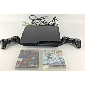 Peut inclure: Une console de jeu PlayStation 3 noire avec deux manettes sans fil noires, un câble d'alimentation et deux boîtiers de jeux vidéo. Les jeux inclus sont Gran Turismo 5 et SSX, présentant chacun leur jaquette et la marque PlayStation 3.