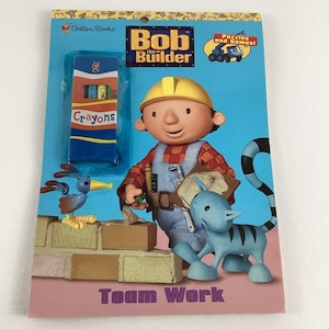 May include: A children's book cover featuring Bob the Builder, a cartoon character, with a blue cat and a bird. The book cover is blue and pink with the title "Team Work" and a box of crayons.