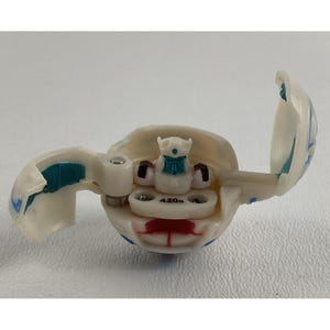 May include: White and blue plastic toy with a clear plastic dome that opens. The toy has a blue and white robot inside. The toy has the number 420 on it.