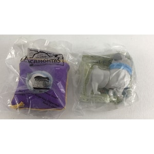 May include: Two plastic bags containing a purple pillow with a Burger King Kids Club logo and a white plastic toy dog wearing a blue scarf. The pillow has the words "Pocahontas" and "Now Available on Disney+" printed on it.