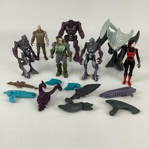 Peut inclure: Une collection de figurines et d'accessoires de science-fiction. Les figurines comprennent des personnages humanoïdes de différentes couleurs et des créatures extraterrestres. Les accessoires comprennent des armes et d'autres petites pièces.