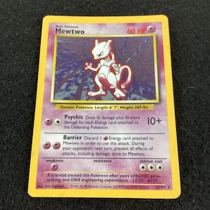May include: A Mewtwo trading card with a yellow border and purple background. The card features the character Mewtwo, 60 HP, and the Psychic attack 10+. Text includes Genetic Pokémon, Length 6' 7", Weight 269 lbs, and 1999 Wizards of the Coast copyright.
