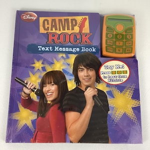 May include: A sealed Disney Camp Rock Text Message Book with a matching orange toy cell phone. The book features images of the movie's stars and the text "Text Message Book". The toy phone has buttons and a small screen.