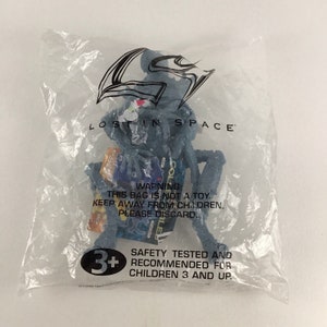 May include: A gray plastic bag with a blue and gray Lost in Space character toy inside. The bag has a warning label that says "This bag is not a toy. Keep away from children. Please discard." and a safety label that says "Safety tested and recommended for children 3 and up."