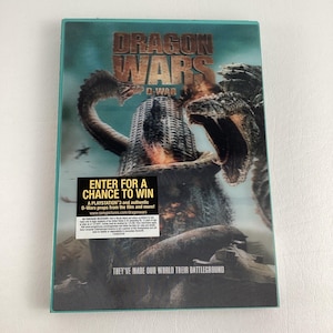 Puede incluir: Carátula de DVD para la película Dragon Wars: D-War. La carátula presenta un fondo verde con dos dragones luchando frente a un edificio alto. El texto "Dragon Wars" está en letras grandes y blancas en la parte superior de la carátula. El texto "D-War" está en letras blancas más pequeñas debajo del título. La carátula también incluye una imagen más pequeña de una consola PlayStation 3 y el texto "Participa para tener la oportunidad de ganar".
