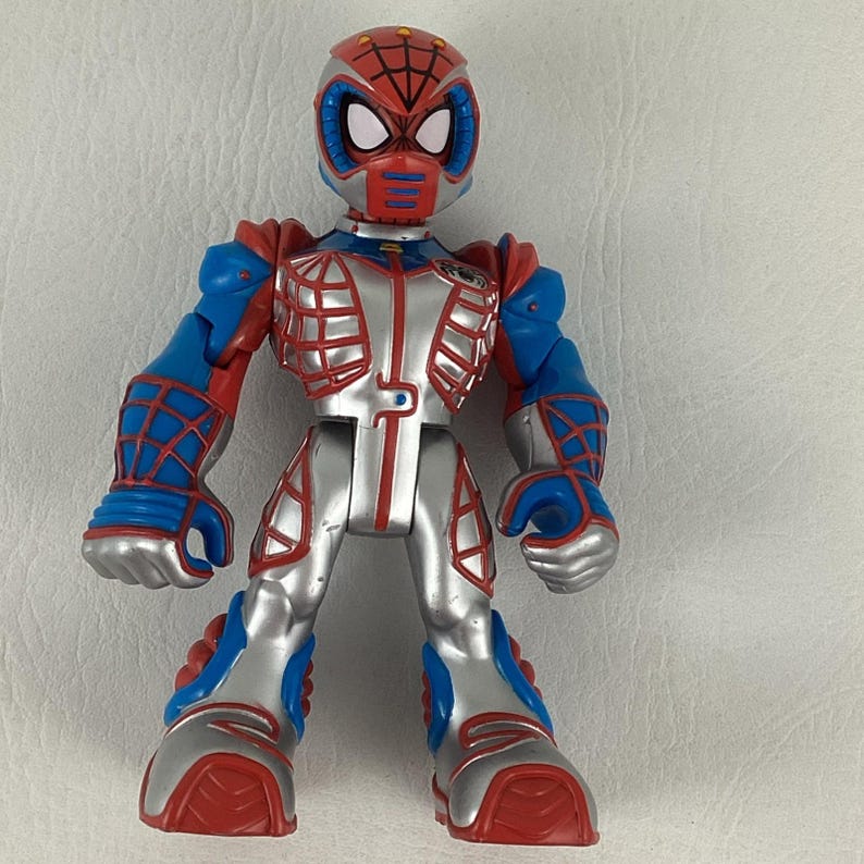 Puede incluir: Una figura de acci&oacute;n de Spider-Man roja, azul y plateada. La figura tiene una m&aacute;scara roja con ojos blancos y un dise&ntilde;o de telara&ntilde;a en la cabeza. El cuerpo es plateado con detalles en rojo y azul. La figura est&aacute; de pie con los brazos a los lados.