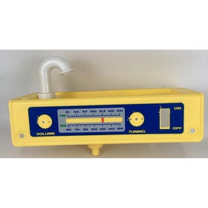 May include: A yellow toy radio with a white faucet-like handle. The radio features a blue panel with volume and tuning knobs, and an AM/FM dial. The radio has an on/off switch and is designed for children.