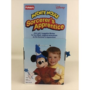 May include: A blue and red Mickey Mouse Sorcerer's Apprentice plush toy with a blue hat and a wand. The plush toy is holding a brown bag. The packaging is blue and white with the words "Mickey Mouse Sorcerer's Apprentice" and "Playskool Disney".
