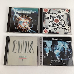 May include: Four compact discs with black cases. The discs feature various rock bands, including Metallica, Led Zeppelin, and a band called "Masters of Metal". The album covers feature band names, album titles, and band logos.