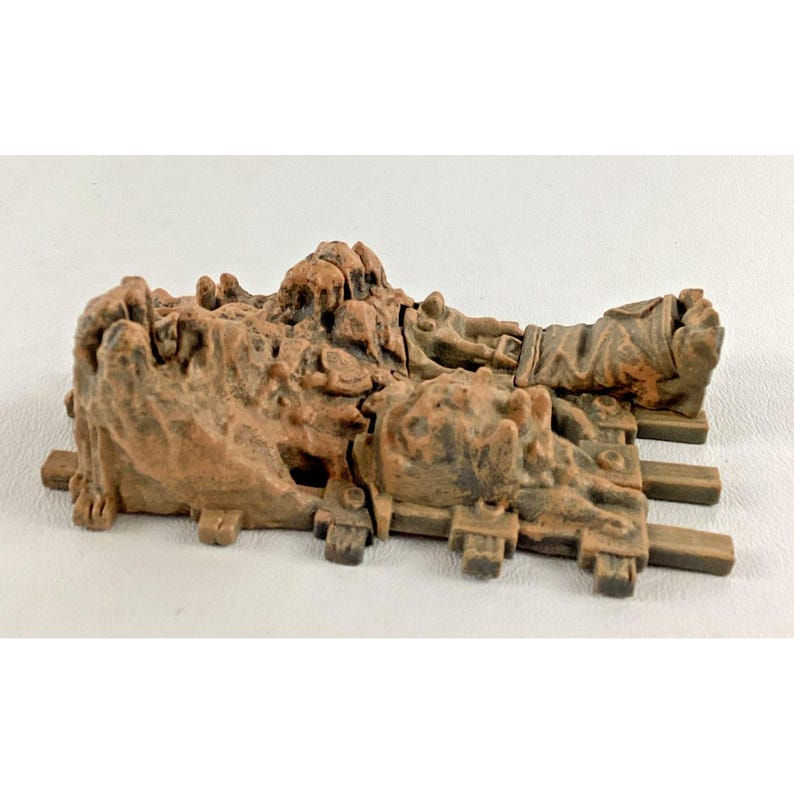 Puede incluir: Una detallada pieza de terreno en miniatura marr&oacute;n, posiblemente para un juego de mesa. Presenta una estructura rocosa texturizada con una figura acostada sobre una plataforma sostenida por vigas paralelas. La pieza est&aacute; dise&ntilde;ada con detalles intrincados y un aspecto desgastado.