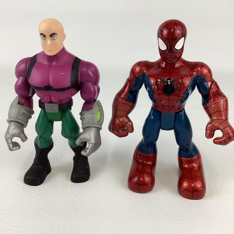 May include: Two action figures: one of Lex Luthor in purple and green, and one of Spider-Man in red and blue. Lex Luthor has a bald head and gray gloves. Spider-Man has a black spider emblem on his chest.