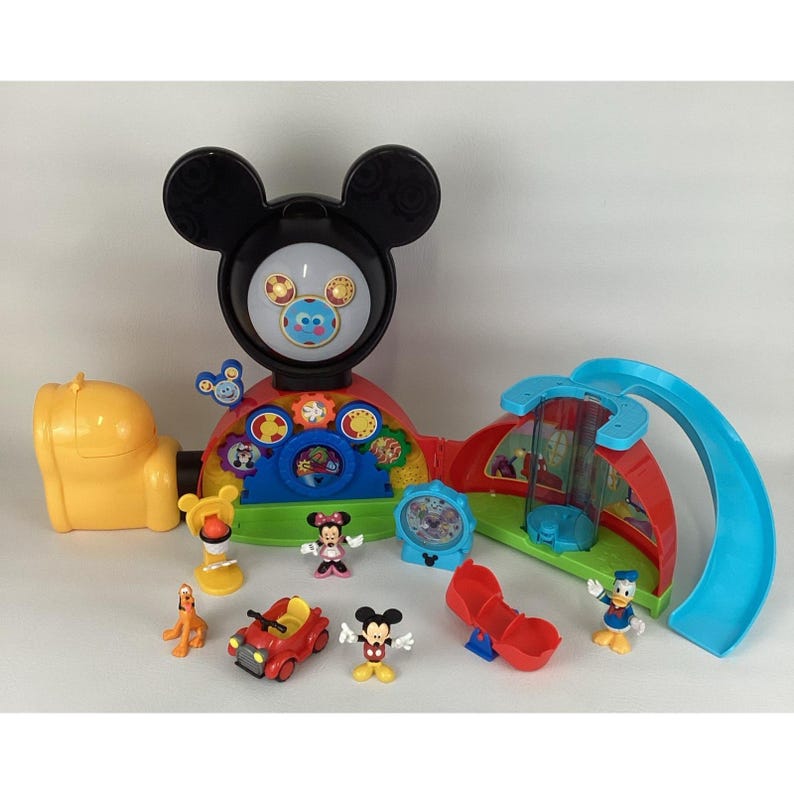 Pu&ograve; includere: Un colorato playset di Mickey Mouse Clubhouse con varie figure e accessori. Il playset presenta una grande testa di Topolino, uno scivolo e diverse statuette di personaggi, tra cui Topolino, Minnie e Paperino. Il set &egrave; in plastica e ha colori vivaci.