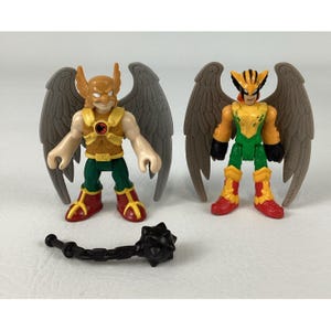 May include: Two winged action figures with moulded grey wings, one wearing a gold helmet and chest piece with a red logo, the other in a yellow and black helmet with green and yellow armour, accompanied by a black spiked mace accessory.