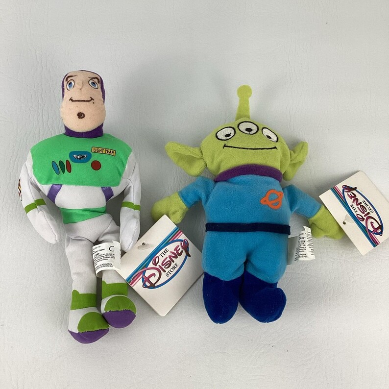 Pu&ograve; includere: Due peluche di The Disney Store. Uno &egrave; un personaggio di Buzz Lightyear con una tuta spaziale bianca, verde e viola. L'altro &egrave; un alieno verde a tre occhi con una tuta blu caratterizzata da un emblema di un pianeta arancione.