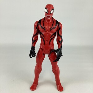 Puede incluir: Figura de acci&oacute;n roja de un superh&eacute;roe con detalles negros. La figura tiene un dise&ntilde;o detallado, que incluye una cara amenazante con dientes afilados y manos en forma de garra. La figura est&aacute; de pie sobre un fondo blanco.