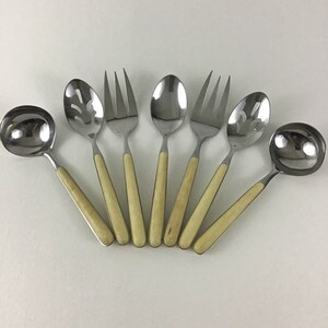 May include: Set of eight silver serving utensils with ivory-colored handles. The utensils include a ladle, a slotted spoon, a serving spoon, and four forks.