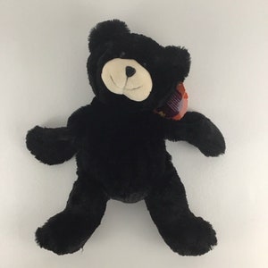 Puede incluir: Oso de peluche negro con cara blanca y ojos negros de botón. El oso está acostado de espaldas con los brazos y las piernas extendidos.