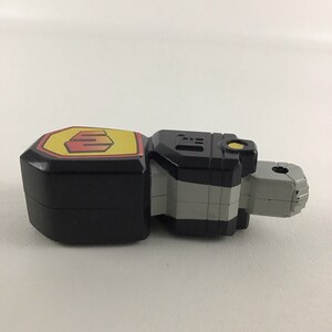 May include: Black and gray plastic toy with a yellow and red emblem that says "E" on the front. The toy has a silver and black section in the middle and a gray section on the end.