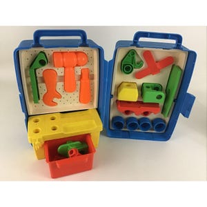 May include: A blue plastic toy toolbox with a yellow drawer and a variety of colorful plastic tools and building blocks inside. The toolbox has a handle on top and a latch on the side.
