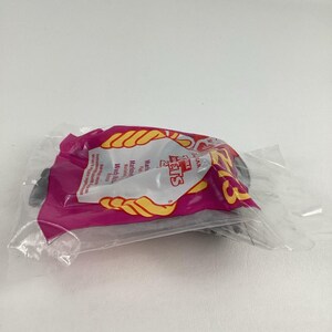 K&ouml;nnte beinhalten: Ein versiegelter Plastikbeutel mit einem Spielzeug. Der Beutel ist rosa mit gelbem und wei&szlig;em Text und Grafiken. Der Text enth&auml;lt die Worte "Fire Pets". Das Spielzeug im Inneren ist teilweise sichtbar.