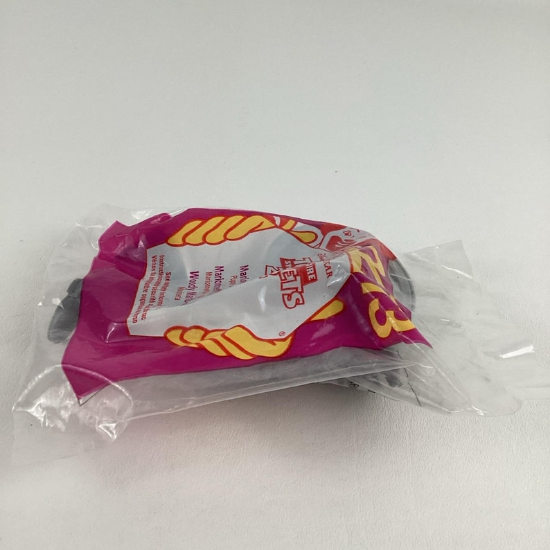 K&ouml;nnte beinhalten: Ein versiegelter Plastikbeutel mit einem Spielzeug. Der Beutel ist rosa mit gelbem und wei&szlig;em Text und Grafiken. Der Text enth&auml;lt die Worte "Fire Pets". Das Spielzeug im Inneren ist teilweise sichtbar.