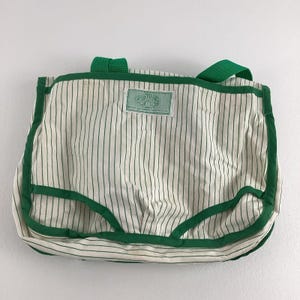 May include: A white canvas tote bag with green stripes and a green trim. The bag has two green handles and a green label that says "Grateful Dead" on it.