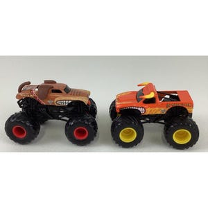 May include: Two toy monster trucks. One is brown with a dog-like design, the other is orange with a bull design. Both have large black tyres with red and yellow accents.