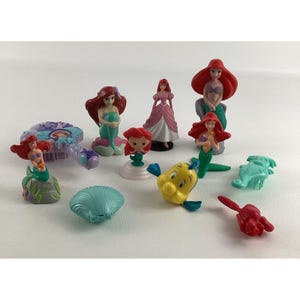 May include: A collection of colorful figurines featuring characters from the animated film, The Little Mermaid. The figurines include Ariel, Flounder, Sebastian, and other sea creatures. The figures are made of plastic and are in various poses.