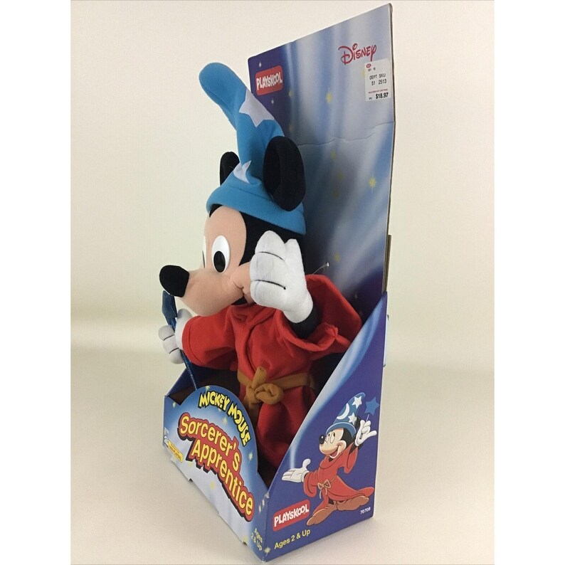 May include: A plush Mickey Mouse toy dressed as a sorcerer's apprentice. He is wearing a blue hat with a star, a red robe, and a yellow sash. The packaging features the words "Mickey Mouse Sorcerer's Apprentice" and "Playskool".