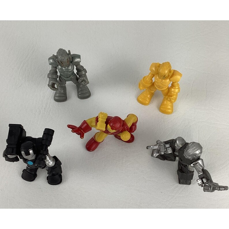 May include: Five toy action figures in various poses. The figures are in shades of silver, yellow, red, and black. The toys appear to be robots or armored characters, possibly from a comic book or movie.