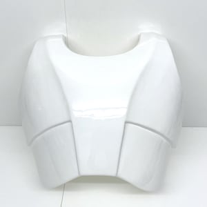 May include: White plastic chest piece with a smooth, glossy finish. The chest piece has a rounded, curved shape with multiple sections.