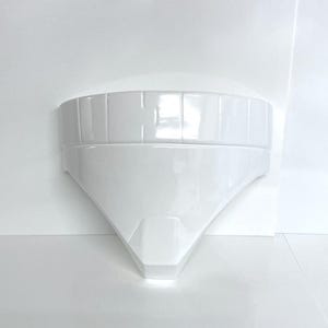 May include: White plastic helmet with a rounded top and a pointed bottom. The helmet has a series of horizontal lines around the top edge.