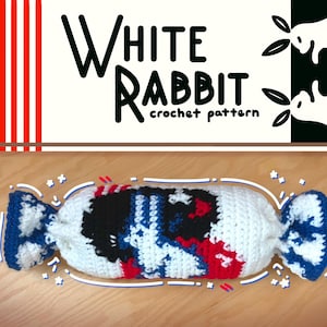 Puede incluir: Un patrón de ganchillo blanco, azul, negro y rojo con forma de caramelo. El texto "White Rabbit crochet pattern" está en la parte superior de la imagen. El patrón de ganchillo está sobre una superficie de madera.