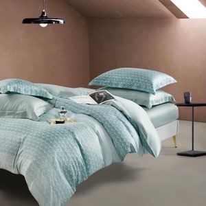 May include: A light blue bed set with a geometric pattern. The bedding is made of soft, luxurious fabric and features a duvet cover, two pillowcases, and a fitted sheet.