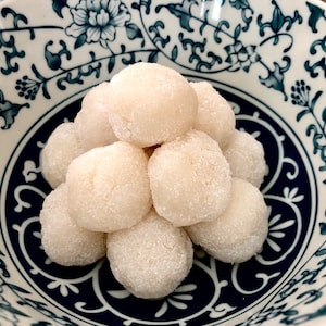 May include: A close-up of a bowl of white mochi balls, arranged in a pyramid shape. The bowl is decorated with a blue and white floral pattern.