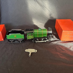 May include: A vintage green and black toy train set with a tender and two red boxes. The train has the number 43746 on the side. A silver key is also included. The set is likely a collectible item.