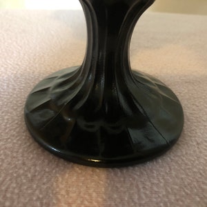 K&ouml;nnte beinhalten: Schwarzer Glassockel mit geriffeltem Sockel. Der Sockel ist aus dunklem Glas und hat eine glatte, polierte Oberfl&auml;che.