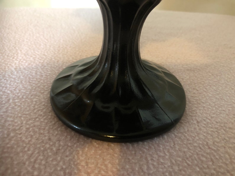 K&ouml;nnte beinhalten: Schwarzer Glassockel mit geriffeltem Sockel. Der Sockel ist aus dunklem Glas und hat eine glatte, polierte Oberfl&auml;che.