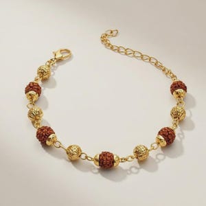 Peut inclure: Bracelet doré avec des perles marron et des sphères dorées décoratives alternées. La chaîne est fine et se ferme avec un fermoir mousqueton. Un accessoire élégant pour un usage quotidien.
